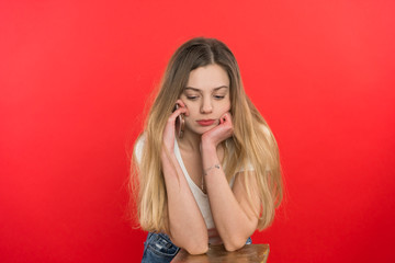 A girl on a red background, stands flat on the surface, she talks on the phone, not fun