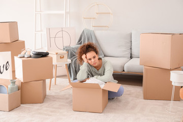 Tired young woman unpacking moving boxes in her new home