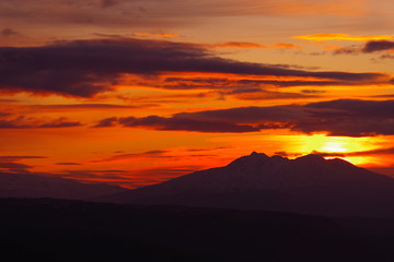 Fototapeta na wymiar 夜明けの太陽に色づいた雲。美しい稜線のシルエット。美幌峠からの朝の眺め。北海道、日本。
