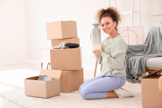 Young woman unpacking moving boxes in her new home