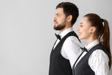 Male and female waiters on grey background