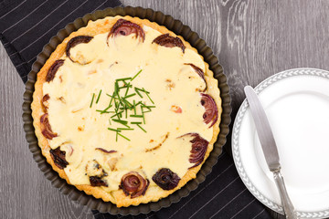 Sheep cheese tart with red onion on wooden background.