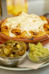 Cheesy nachos with guacamole and jalapenos.