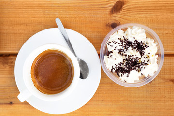 White ceramic cup of coffee and piece of dessert with cream.
