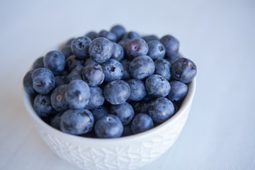 Blueberries in the ceramic bowl on the table. Natural day light. Top view