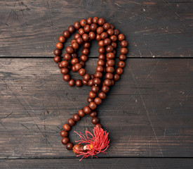 wooden prayer rosary on a brown wooden table, top view