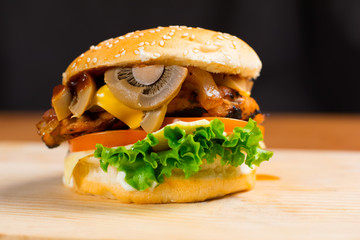 A Delicious Gourmet Burger Topped With Swiss Cheese And Fried Mushrooms on Wooden Table
