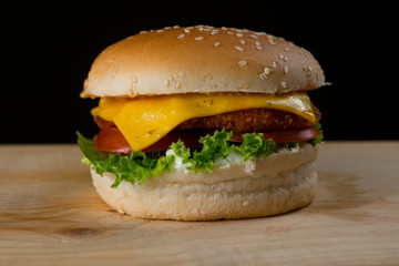 Fresh and Juicy Burger on a Wooden Table with Cheese Lettuce and Tomato