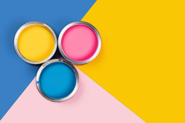 Repare concept. Tricolor blue, yellow, pink background with three colors paint cans. Flat lay, top...