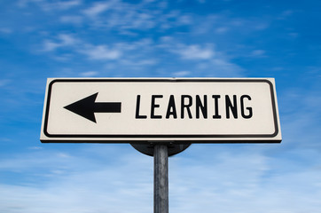 White sign with arrow - Learning. Direction sign. Crossroads Road Sign, arrow on blue sky background. Arrows on a pole pointing in one direction. Learning in that direction. Never stop learning.