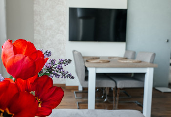 bright red tulips and lilacs in the kitchen on the background of the dining table