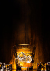 ice falls into a glass with expensive whiskey and spray flies in different directions