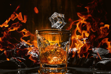 ice falls into a glass with expensive whiskey and spray flies in different directions