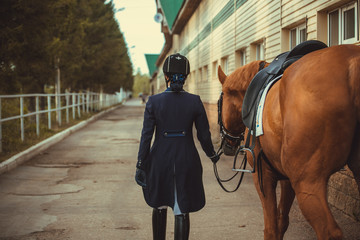 Rider woman with the horse are walking in a stable outdoors for dressage training