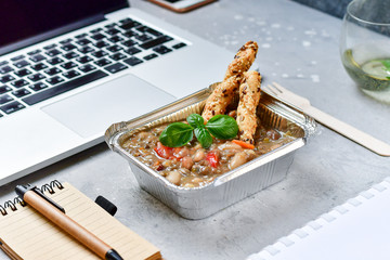 Food delivery. lunch box with a diet lunch or dinner on grey office table. Stewed beans with vegetables, takeaway lunch at the office. Top view. takeout healthy lunch. selective focus