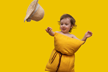 a beautiful little girl with a yellow pillow on her belt catching a flying hat on a bright yellow background - stylish hat at any time, useful orthopedic pillows