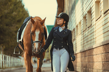 Rider woman with the horse are walking in a stable outdoors for dressage training - 344500742