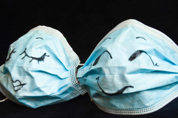 Two funny protection masks against Corona, with faces, like a man and a woman, are flirting...