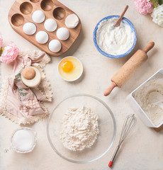 Modern baking background with flour in bowl, eggs and ingredients on white kitchen table background, top view. Home Bake. Recipes to cookies, pie and cake