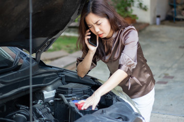 Fototapeta na wymiar asia angry woman looking at broken down car engine and holding mobile phone calling for help