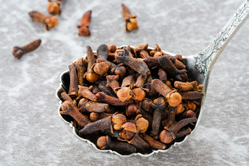 Whole cloves in a spoon - closeup with selective focus