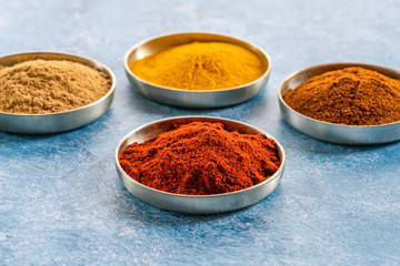 Ground spices in pots -  paprika, tumeric, chilli and curry powder - closeup with selective focus