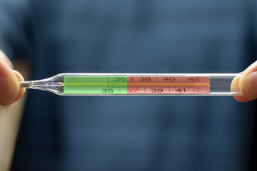 thermometer in hands close-up on a blue background