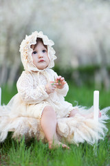 Little baby girl in vintage dress and hat in spring garden