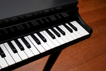 Fototapeta na wymiar Piano with black and white keys on a wooden floor background