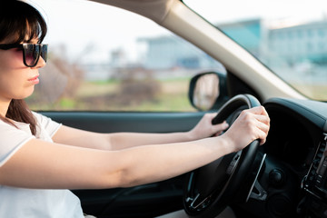 Naklejka premium Caucasian female holding hands on a steering wheel when drive her car through the city traffic jam. looking concentrated . safety driving concept