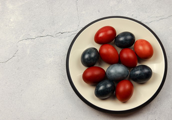 Easter natural colored eggs on a white round plate on a light gray background. Top view, flat lay