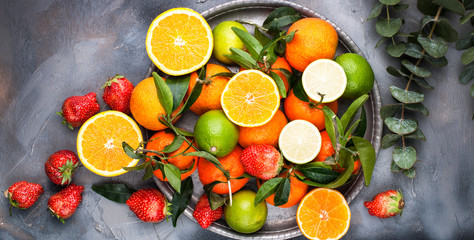 Assorted fruits. Different fruits on a gray background, the whole surface is covered with citrus fruits, pomegranates, apples, grapes, strawberries. Top view. Copy space. Banner