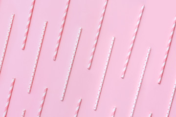 Pattern of pastel paper straws with white stripes and dots on soft pink background. Festive zero waste concept. Flat lay style.