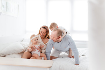Obraz premium A young happy family with young children lying around, hugging, laughing on the bed at house