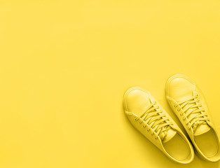 Yellow leather sneakers on yellow background. Pair of yellow sport shoes or sneakers with copy space for text or design. Overhead shot of new yellow sneakers, monochrome. Top view or flat lay