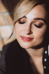 Beautiful young woman blonde in jeans with a polka dot jacket and a scarf in her hair in a loft studio near the window with sunbeams. Soft selective focus.