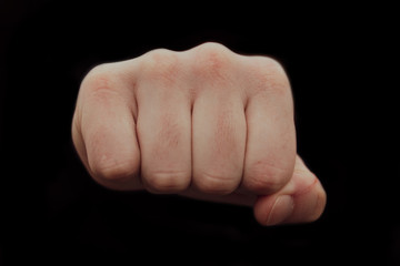 Hand clenched a fist on a black background. male punch close up