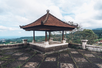 old wooden gazebo with a red roof on a brick floor