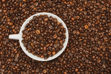 top view on a cup with coffee grains on a background of coffee beans close-up. copy space
