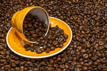 Coffee beans. Yellow coffee cup with a plate on a background of coffee beans close-up
