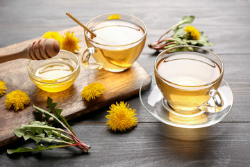 Cups of healthy dandelion tea with honey on table