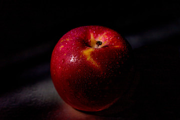 Red apple fruit in low light.