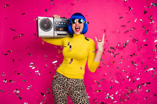 Photo of crazy festive lady rocker party confetti fall vintage recorder on shoulder show horns wear specs yellow turtleneck blue wig leopard pants isolated bright pink color background