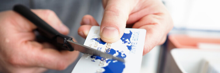 Male hand cutting banking card with scissors