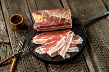 Salted bacon on wooden board with pepper fork knife smoke wooden texture cuisine daylight