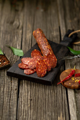 Dried sausage on wooden board with spices chili pepper wooden texture cuisine