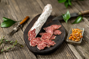 Dried sausage on wooden board with spices chili pepper wooden texture cuisine