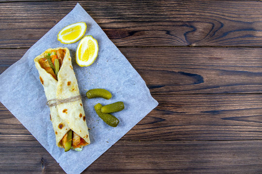 Delicious Turkish Doner Kebab On Pita Bread With Shaved Roasted Meat Off A Traditional Vertical Rotisserie Served With Fresh Salad Ingredients On Rustic Paper, Stand On Wooden Table