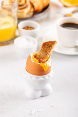 Delicious breakfast with soft boiled eggs, toasted bread, cup of coffee and orange juice.