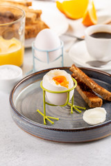 Delicious breakfast with soft boiled eggs, toasted bread, cup of coffee and orange juice.